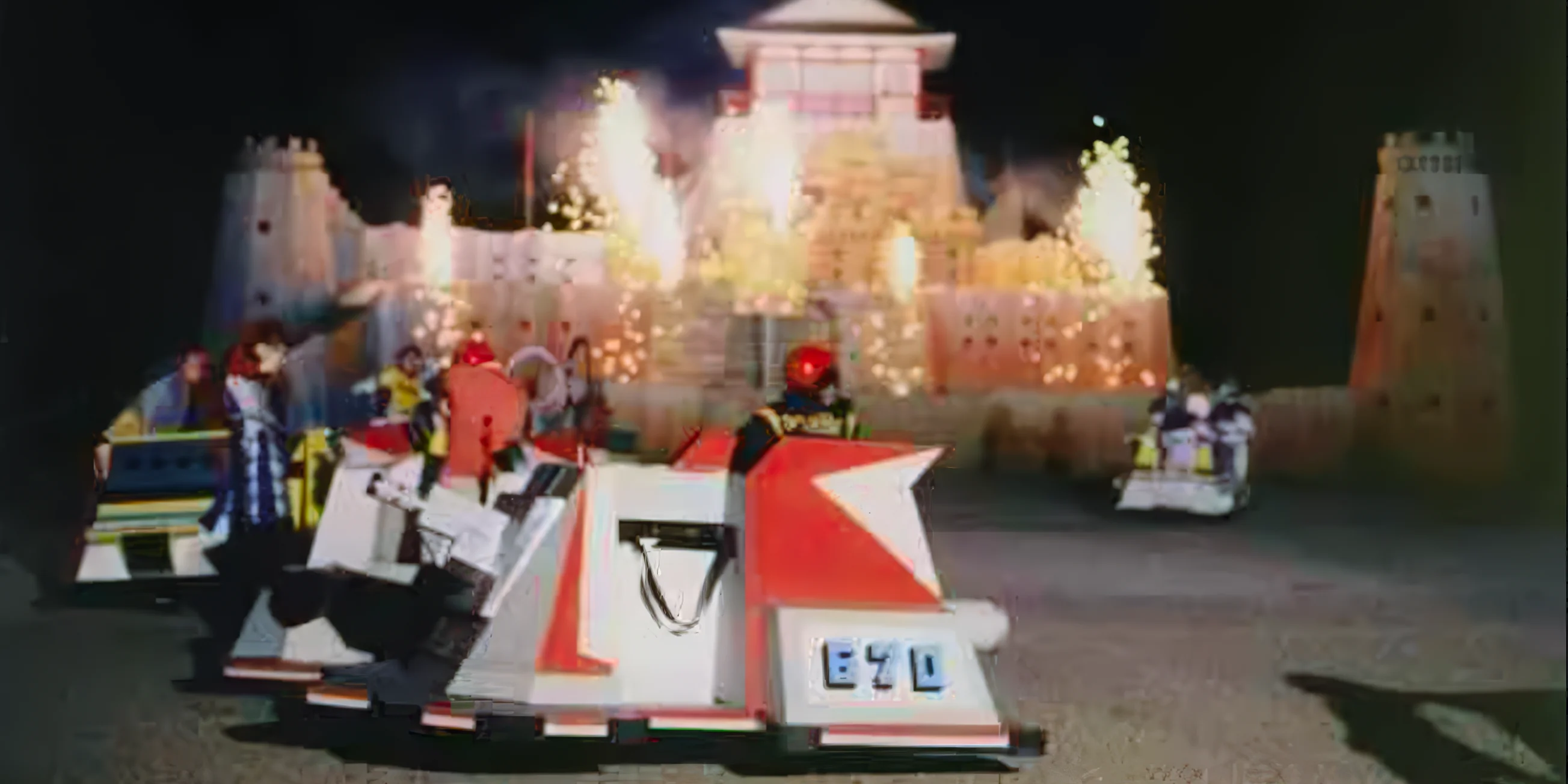 Pyrotechnics fire on Takeshi's Castle while contastants and guards dry by in carts at the end of the Show Down